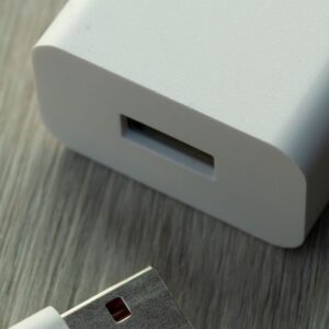 A detailed view of a white USB charger and cable on a wooden surface.