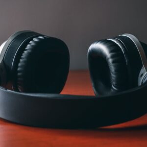 Close-up of sleek wireless headphones placed on a polished wooden surface under soft studio lighting.
